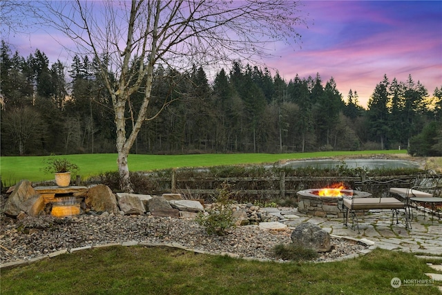 yard at dusk with a water view and an outdoor fire pit