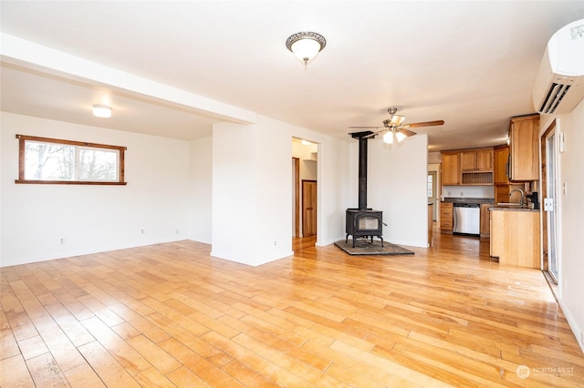 unfurnished living room featuring sink, light hardwood / wood-style floors, a wood stove, and an AC wall unit