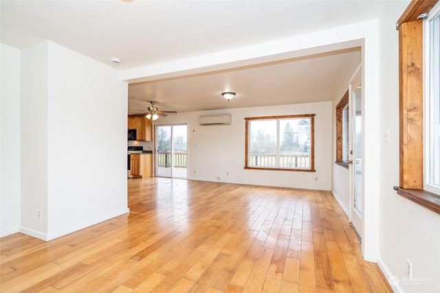 unfurnished living room with a wall mounted air conditioner, light hardwood / wood-style flooring, and ceiling fan