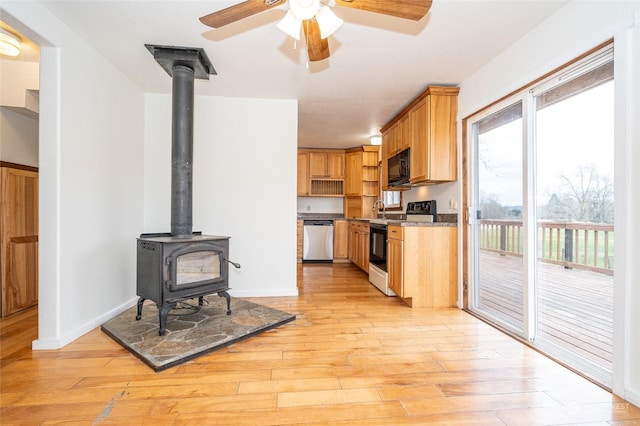 kitchen featuring white range with electric cooktop, dishwasher, light hardwood / wood-style floors, and a wood stove