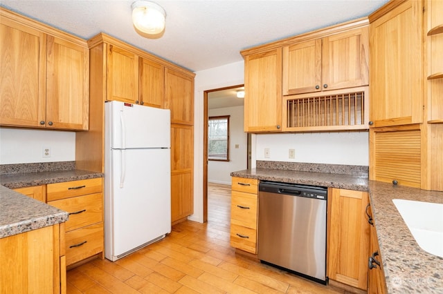 kitchen with sink, white fridge, stainless steel dishwasher, light brown cabinets, and light wood-type flooring