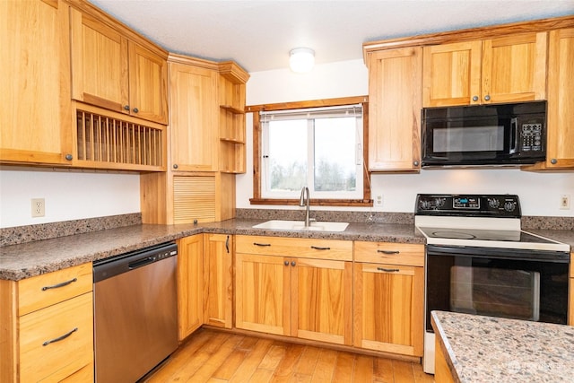 kitchen featuring sink, black appliances, dark stone counters, and light wood-type flooring