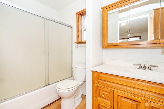 full bathroom featuring enclosed tub / shower combo, vanity, and toilet