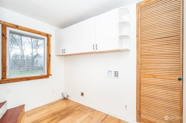 clothes washing area with cabinets, electric dryer hookup, washer hookup, and light wood-type flooring