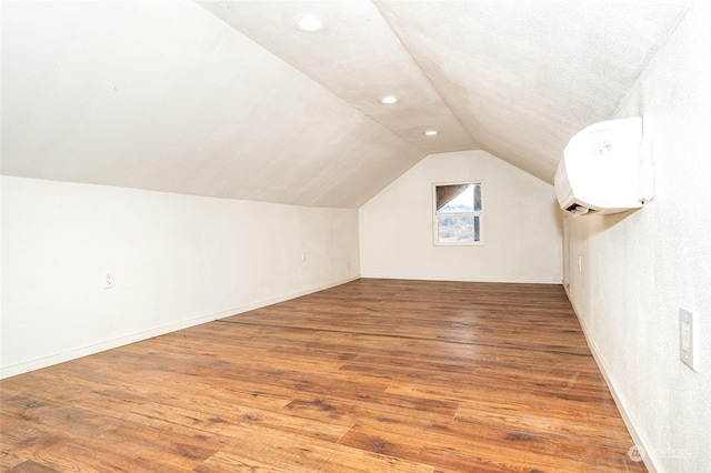 bonus room featuring wood-type flooring, vaulted ceiling, and a wall mounted air conditioner