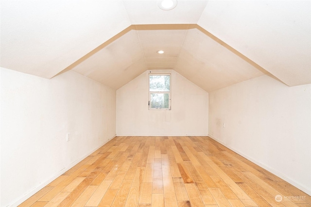 additional living space with hardwood / wood-style flooring and lofted ceiling