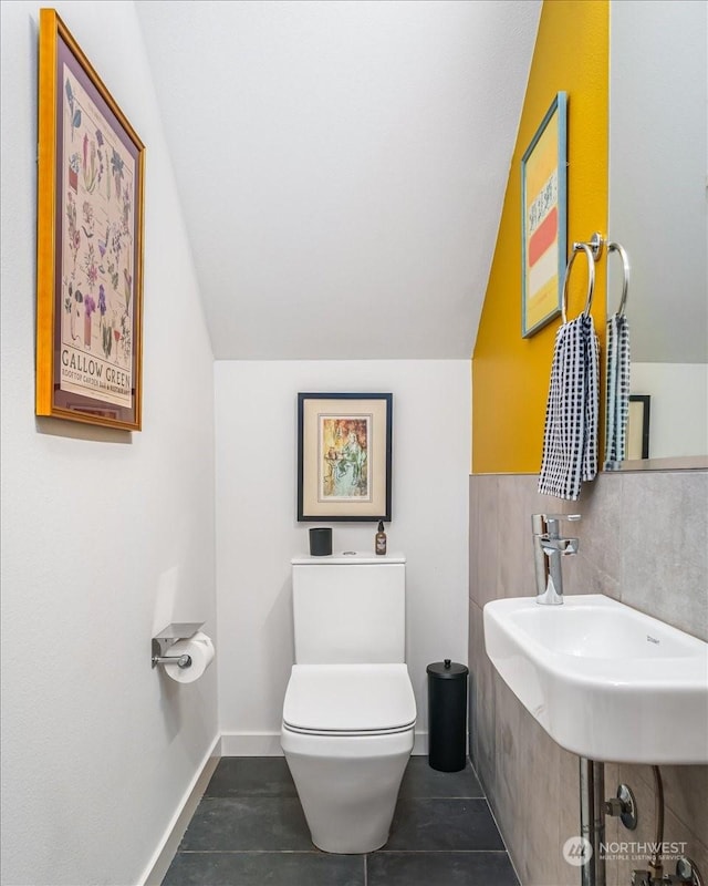 bathroom with lofted ceiling, sink, tile patterned floors, and toilet