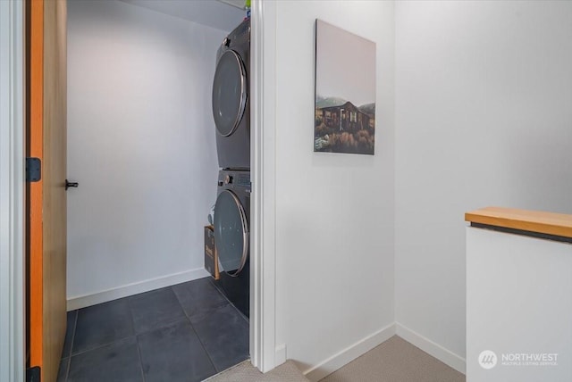 laundry area featuring stacked washer and dryer and dark tile patterned flooring