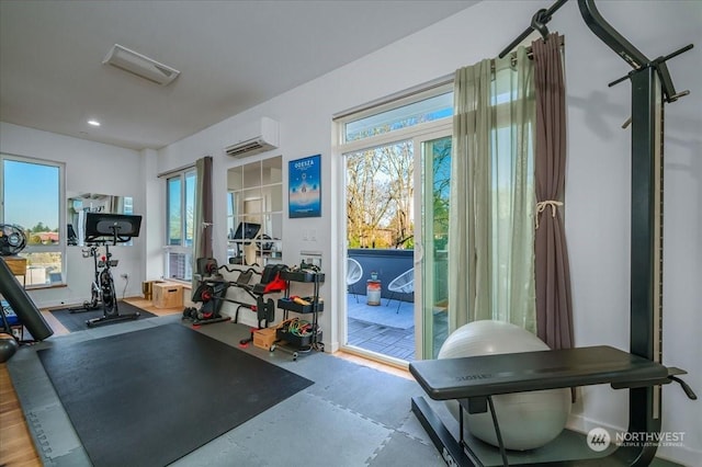 workout room featuring plenty of natural light and an AC wall unit