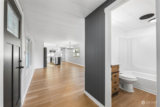 corridor with a chandelier and light hardwood / wood-style flooring