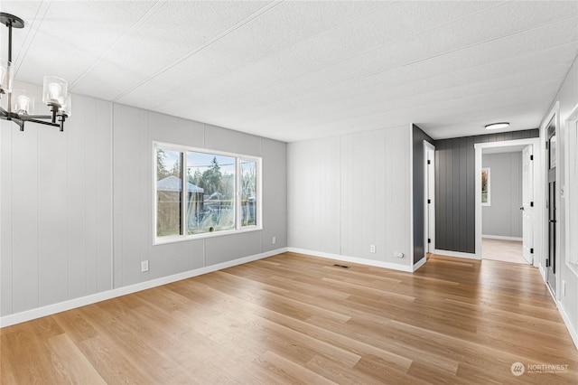 empty room featuring hardwood / wood-style floors and a notable chandelier