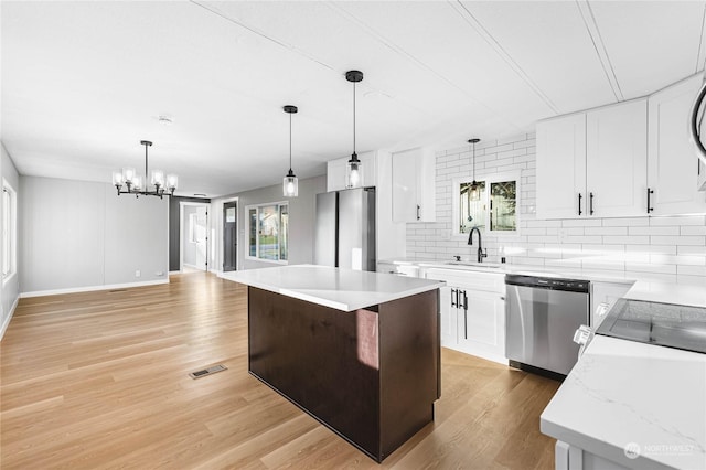 kitchen with stainless steel appliances, white cabinetry, a center island, and light wood-type flooring