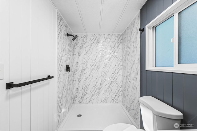 bathroom featuring tiled shower and toilet