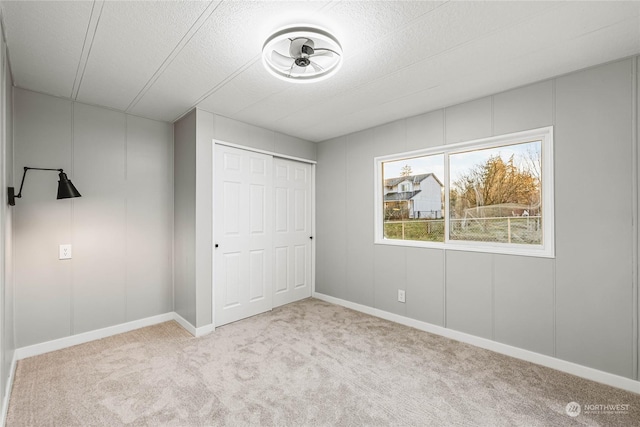 unfurnished bedroom featuring light carpet, a closet, and a textured ceiling