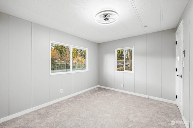 unfurnished room with light colored carpet and a textured ceiling