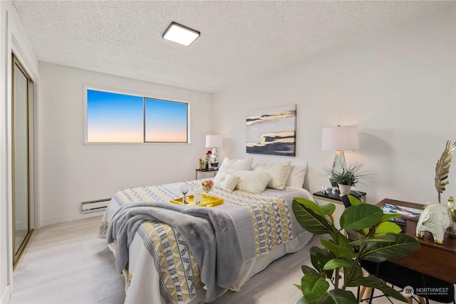 bedroom featuring baseboard heating, a closet, a textured ceiling, and light wood-type flooring