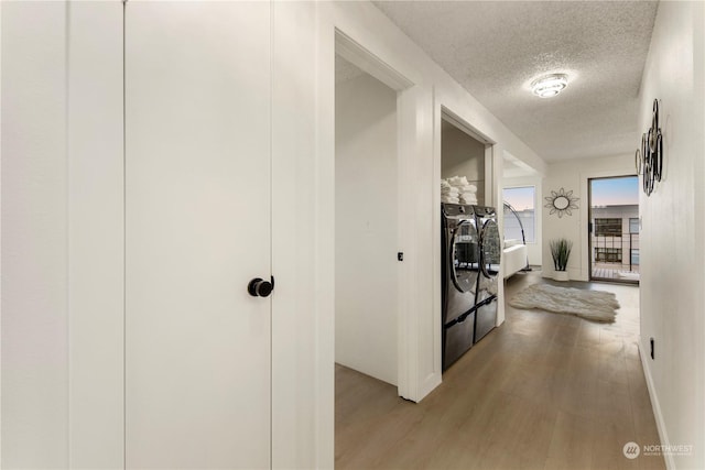 hallway featuring hardwood / wood-style flooring, washing machine and clothes dryer, and a textured ceiling