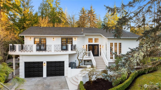 view of front facade featuring a garage, a balcony, and french doors