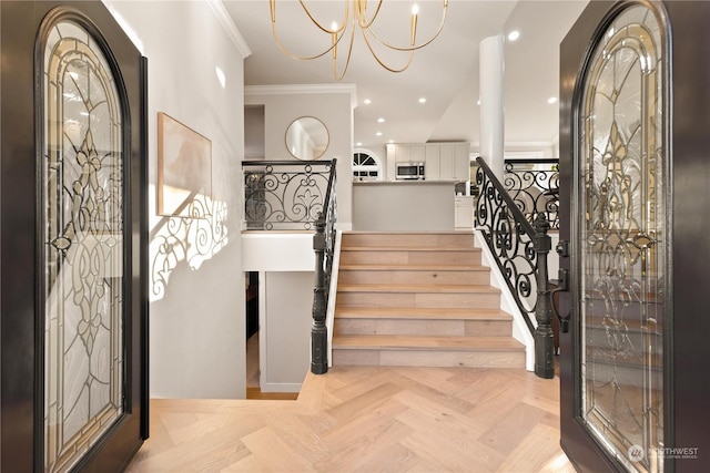 entryway featuring crown molding, a chandelier, and light parquet floors