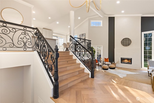 staircase featuring parquet floors, a large fireplace, ornamental molding, and high vaulted ceiling