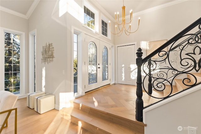 entryway featuring a notable chandelier, crown molding, a healthy amount of sunlight, and a towering ceiling