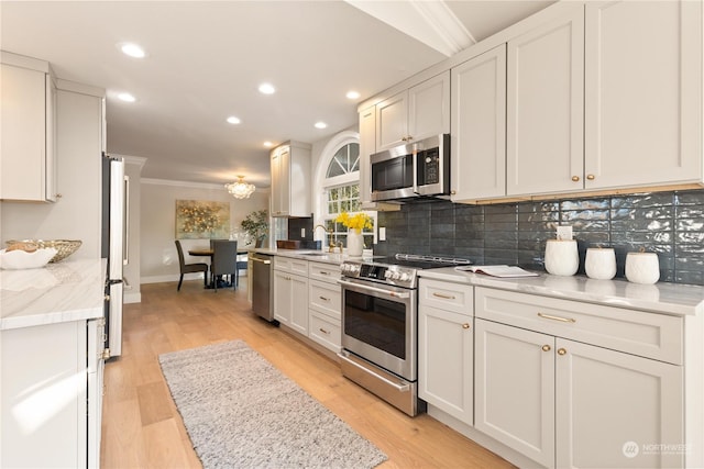 kitchen featuring white cabinetry, backsplash, light hardwood / wood-style floors, stainless steel appliances, and light stone countertops