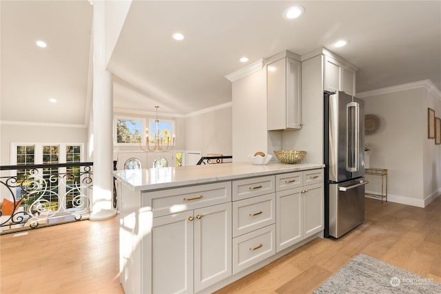 kitchen featuring high end fridge, light stone counters, crown molding, light wood-type flooring, and white cabinets