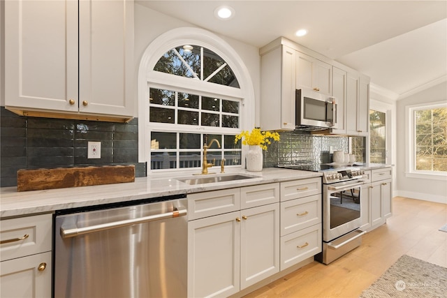 kitchen featuring stainless steel appliances, light stone countertops, sink, and white cabinets