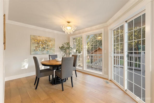 dining area with ornamental molding, a chandelier, and light wood-type flooring