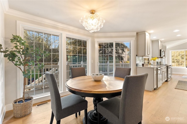 dining room with crown molding, a chandelier, and light wood-type flooring