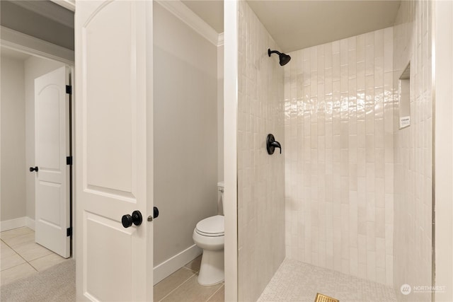 bathroom with tile patterned flooring, a tile shower, and toilet