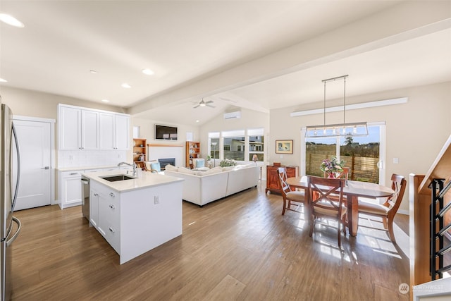 kitchen with pendant lighting, sink, white cabinets, a center island with sink, and dark hardwood / wood-style flooring