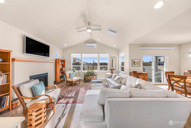 living room featuring vaulted ceiling, hardwood / wood-style floors, ceiling fan, and a wall unit AC