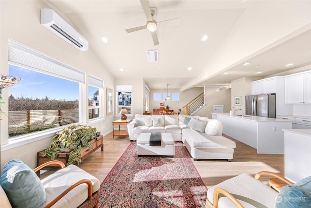 living room featuring an AC wall unit, high vaulted ceiling, sink, ceiling fan, and light hardwood / wood-style floors