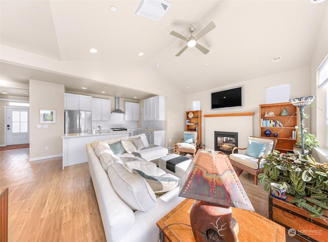 living room featuring ceiling fan, lofted ceiling, and light hardwood / wood-style floors