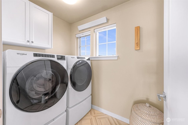 washroom featuring cabinets, light parquet flooring, and washer and dryer