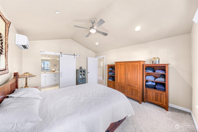 bedroom featuring lofted ceiling, ensuite bath, an AC wall unit, light colored carpet, and a barn door