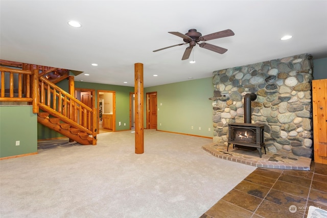 carpeted living room with ceiling fan and a wood stove