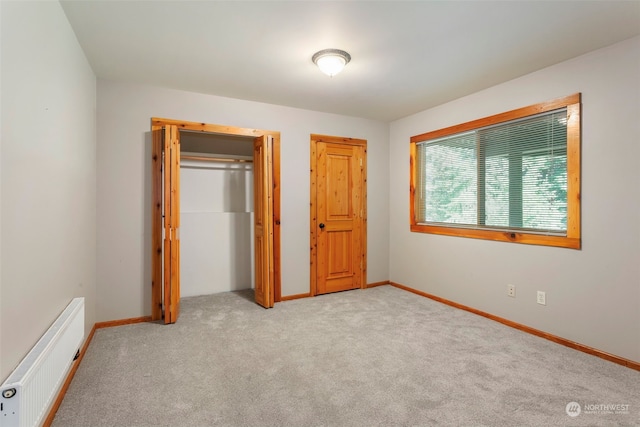 unfurnished bedroom featuring light colored carpet and radiator heating unit