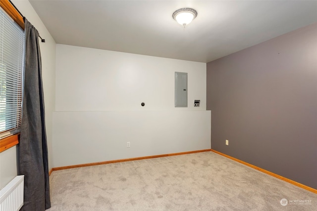 spare room with light carpet, radiator heating unit, and electric panel