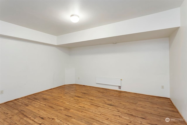 basement featuring radiator and light hardwood / wood-style floors