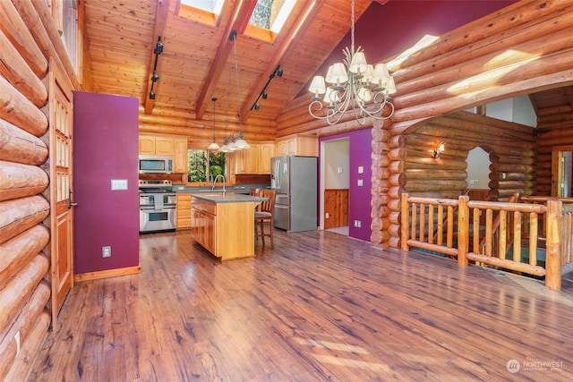 kitchen with appliances with stainless steel finishes, decorative light fixtures, sink, a breakfast bar area, and a center island