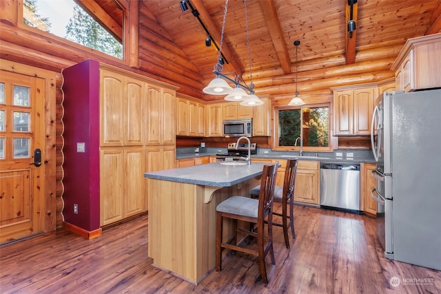 kitchen featuring dark wood-type flooring, appliances with stainless steel finishes, hanging light fixtures, and a center island with sink