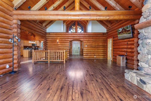 unfurnished living room featuring hardwood / wood-style flooring, rustic walls, high vaulted ceiling, wooden ceiling, and beamed ceiling