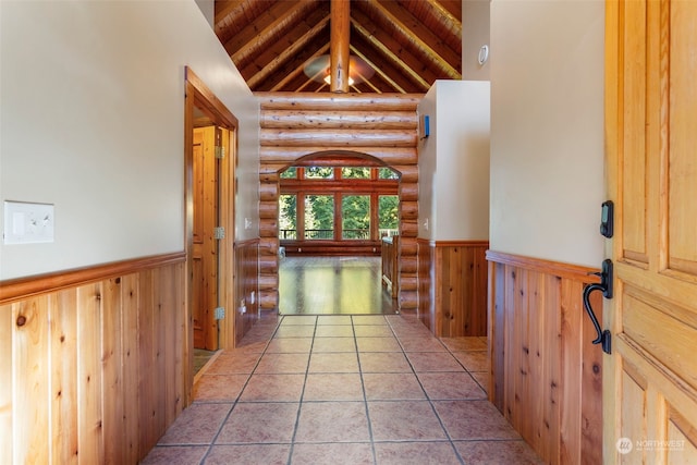 hallway with wood ceiling, rustic walls, light tile patterned floors, and vaulted ceiling with beams