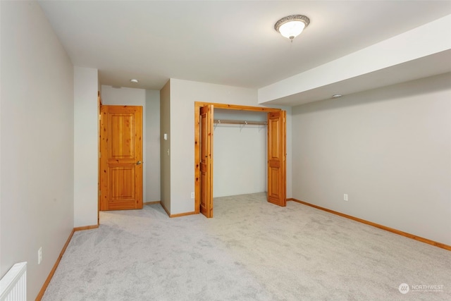 unfurnished bedroom with light carpet, radiator heating unit, and a closet