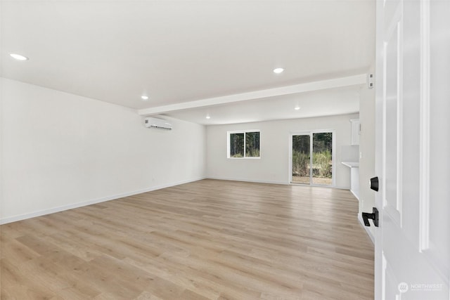 unfurnished room with beam ceiling, a wall mounted AC, and light wood-type flooring