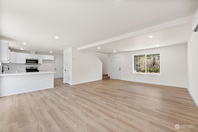 unfurnished living room featuring sink and light wood-type flooring