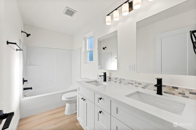 full bathroom featuring hardwood / wood-style flooring, shower / washtub combination, toilet, and vanity