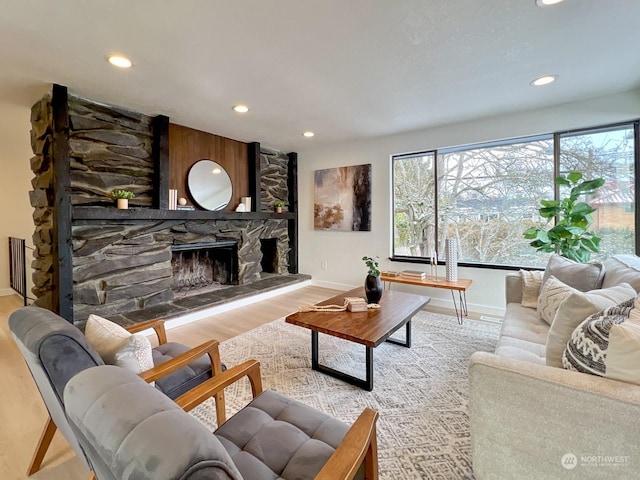 living room with a stone fireplace and light hardwood / wood-style flooring